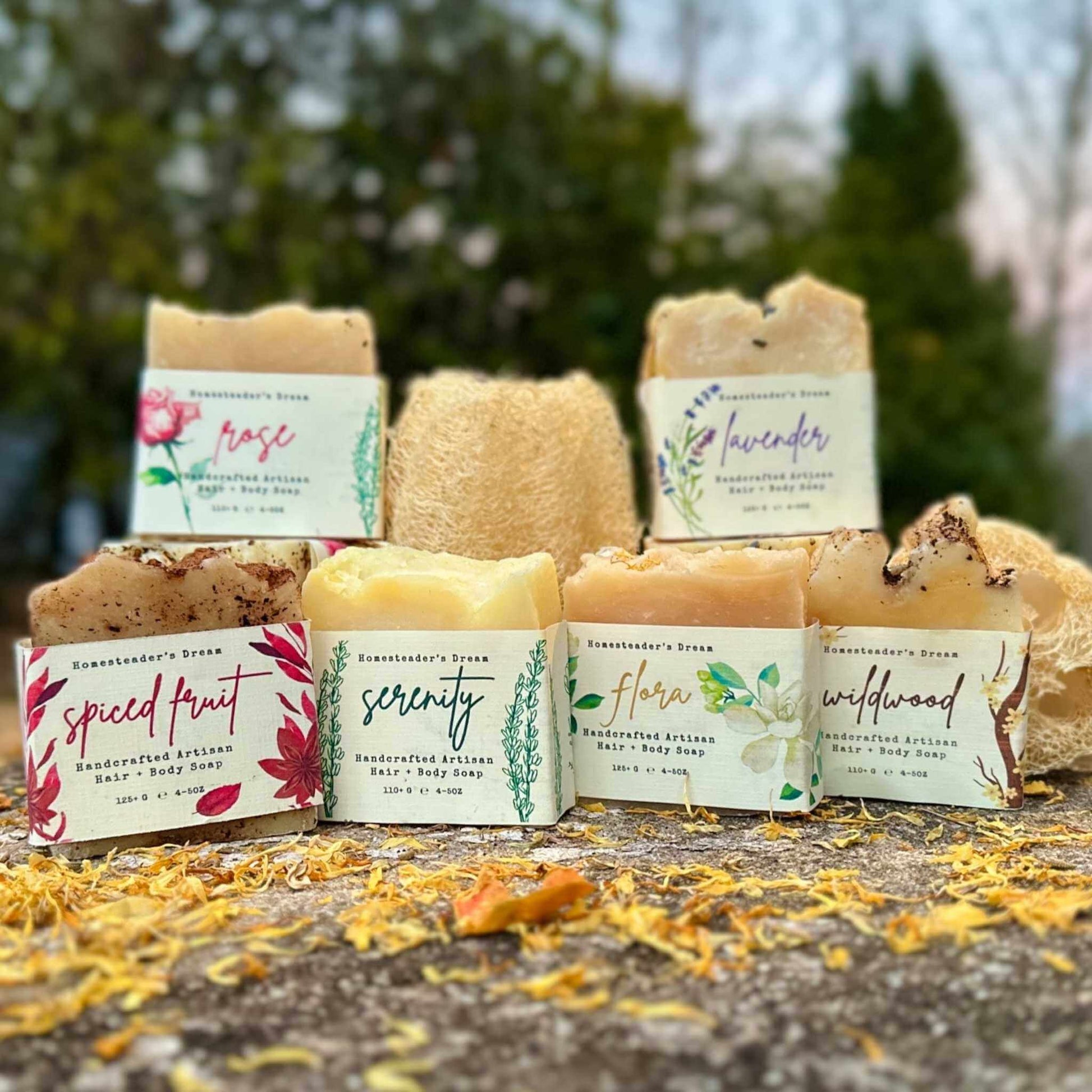 Collection of handmade soap bars with labels on a stone surface outdoors.