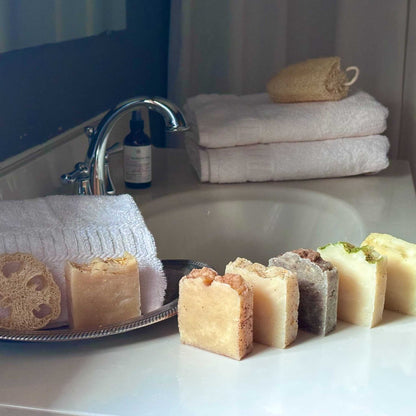 Bathroom counter with soap, loofahs, towels, and a bathtub in the background