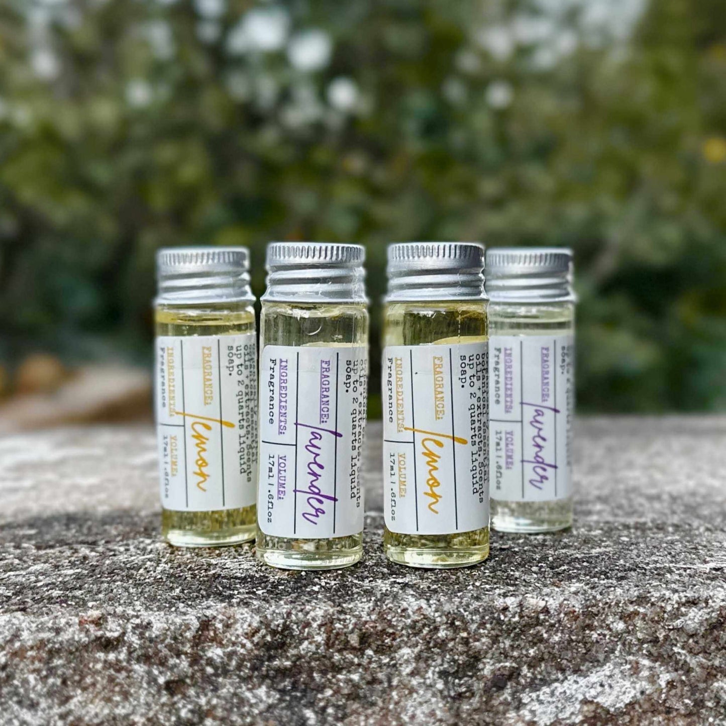 Four small glass bottles with labels on a textured surface with a blurred green background