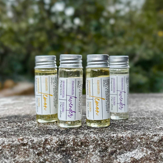 Four small glass bottles with labels on a textured surface with a blurred green background