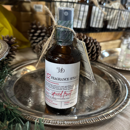 4 oz glass spray bottle of spiced fruit spray on a silver tray with a pinecone