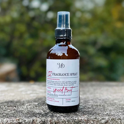 Fragrance spray bottle labeled 'Spiced Fruit' on a stone surface with a blurred green background