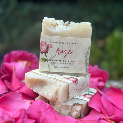 Stack of artisanal rose soap bars with decorative floral patterns, placed on a bed of pink rose petals.
