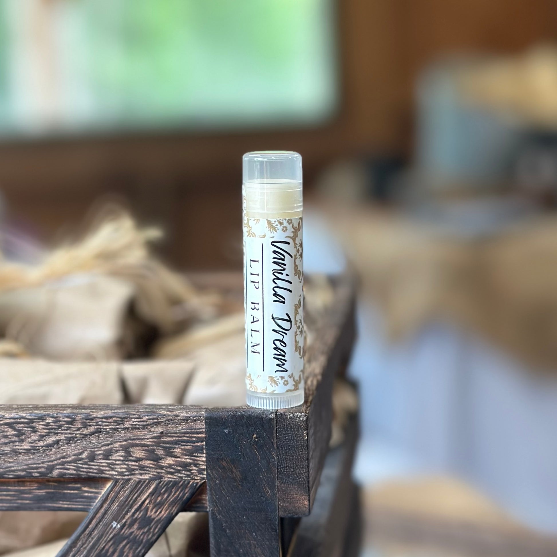 A tube of Vanilla Dream lip balm set on a wooden surface with a blurred background.