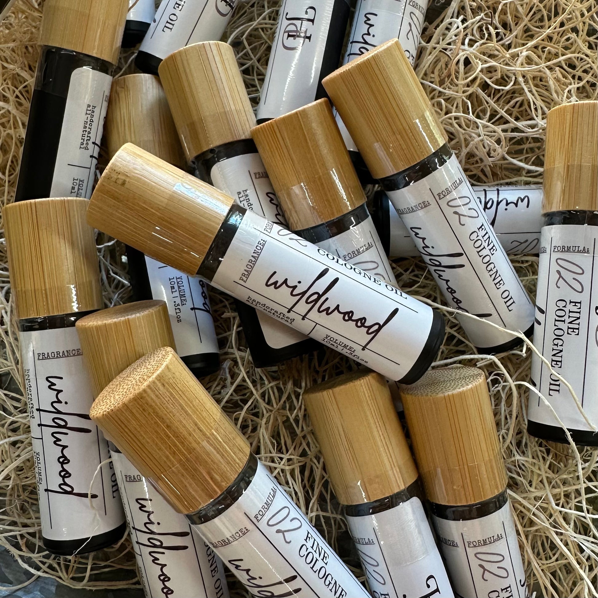 Roll-on bottles of cologne labeled 'Wildwood' on a straw background